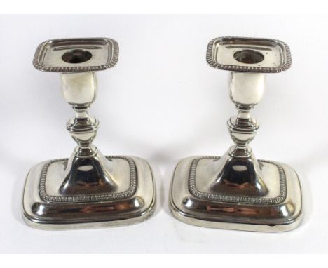 A pair of George V silver candlesticksEach with a rectangular loaded base and undulating stem with grooved rims, William Hutt