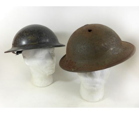 A WWII period painted metal brodie type helmet The helmet with two holes, with inner lining, further black helmet with lining