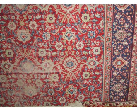 A very substantial wool carpet in the Persian style with red ground field and abstract floral decoration within alternating b