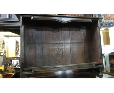 An Edwardian oak open bookcase with applied mouldings, containing one shelf, 105 cm wide