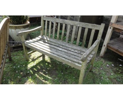 A weathered teak two seat garden bench with slatted seat and back (AF).