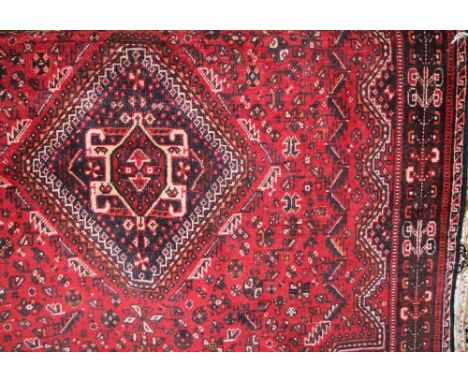 A Persian style red ground wool carpet set within further running red borders and with geometric decoration, 220 x 150 cm app