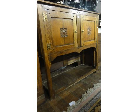 A panelled oak cupboard on stand with pegged frame, the upper section enclosed by two panelled doors, the lower section with 