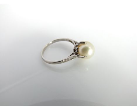 An early 20th century platinum pearl and diamond ladies dress ring, centrally set with a single full 9mm pearl in a four pron