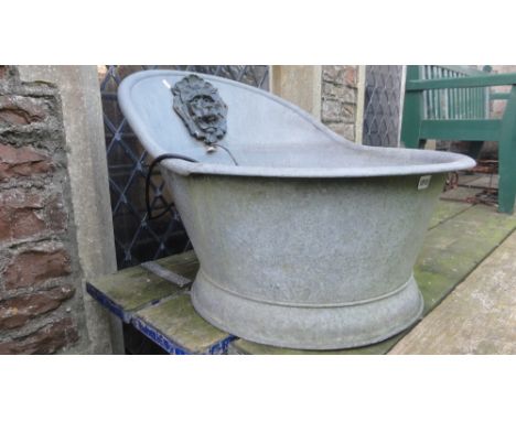 A vintage galvanised hip bath, later converted to a water feature with applied lions mask spout