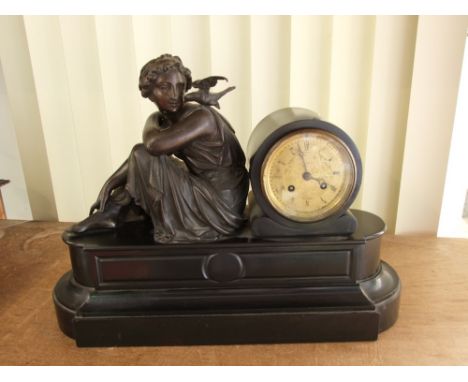French black slate drum head figural mantle clock, mounted by a recumbent classical female character with a bird on her shoul