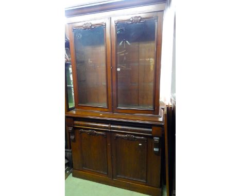 A mid Victorian mahogany library bookcase, the lower section enclosed by two panelled doors and two cushion moulded frieze dr