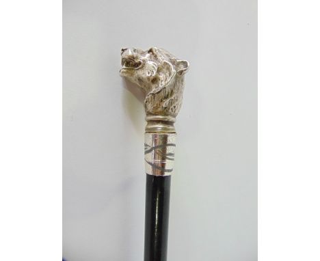 An ebonised walking stick with white metal collar and knop in the form of a snarling dog, 91 cm long approx.