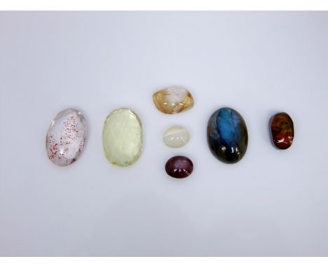 A collection of unmounted gemstones to include an oval labradorite cabochon, a star ruby, a free-cut fire agate, a cats eye o