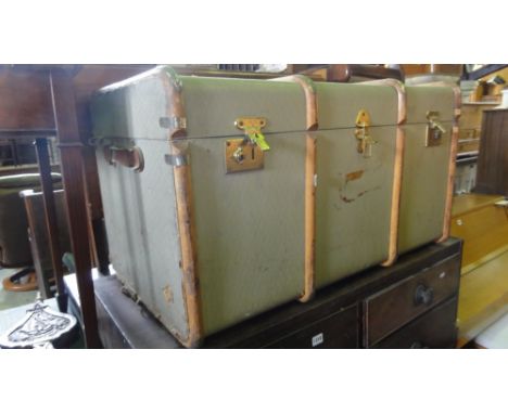A vintage travel trunk with chequered covers and timber lathes
