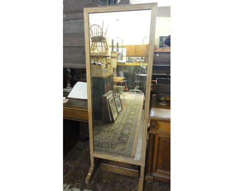 An Art Deco cheval glass in a fumed oak frame on simple cut supports, 178 x 64 cm approx.