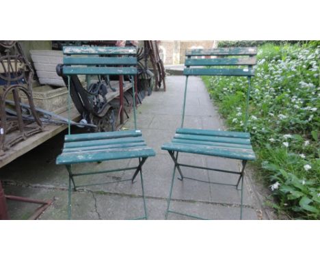A pair of vintage green painted folding steel framed garden chairs with soft wood slatted seats and backs