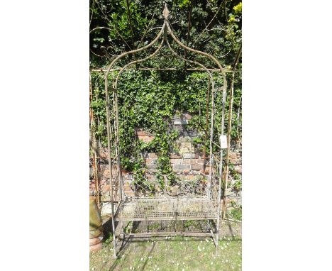 A contemporary tubular steel framed arbour with open scrollwork panelled sides and bench seat with lattice panel beneath a sh