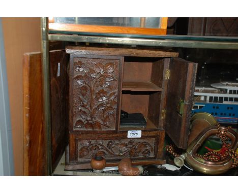 A small carved Oak pipe/smoker's Cabinet with miscellaneous pipes, etc.