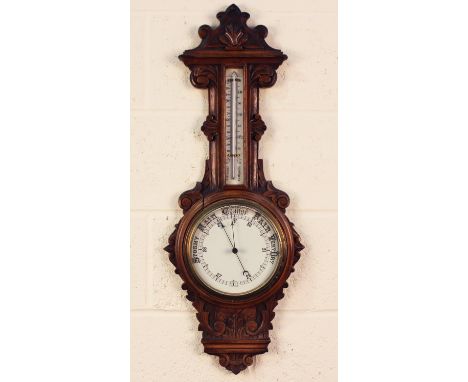 A late Victorian oak cased wheel barometer with mercury thermometer and ceramic dials, the case with carved decoration, heigh