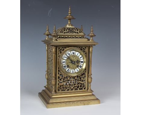 A late Victorian brass cased mantel clock with eight day movement striking on a gong, the embossed brass dial inset with enam