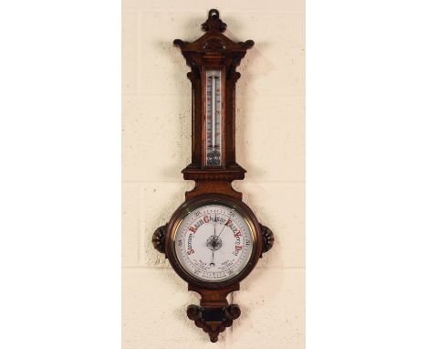 A late Victorian oak aneroid wheel barometer with ceramic dial and mercury thermometer, the case with carved decoration, heig