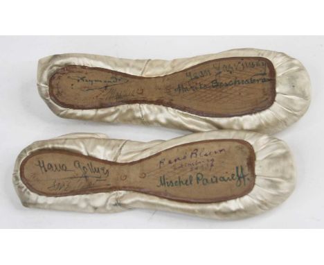 A pair of vintage silk children's ballet pump shoes, each bearing signatures to the sole