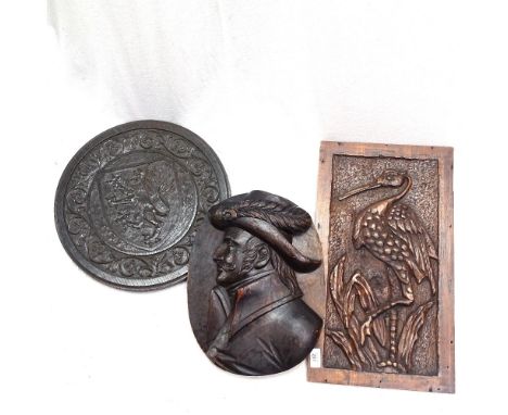 A carved oak panel with shield design, 40cm, another with curved wading bird, and a carved pine panel with portrait decoratio