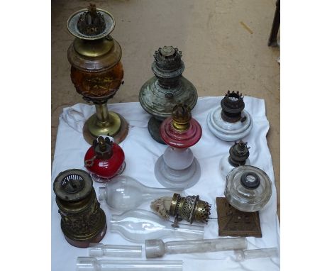 A brass oil lamp with amber glass font, and other oil lamps and chimneys 