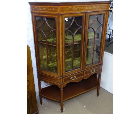 An Edwardian mahogany and satinwood-banded display cabinet, of canted form, with 2 lattice-glazed doors, drawers under and sh