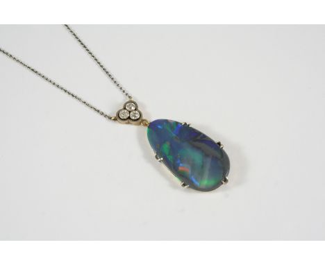 A BLACK OPAL AND DIAMOND PENDANT the pear-shaped solid black opal is mounted in gold, with three circular-cut diamonds collet