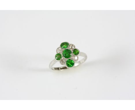 A DEMANTOID GARNET AND DIAMOND CLUSTER RING set with five circular-cut garnets and four cushion-shaped diamonds, in 18ct. gol