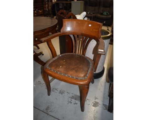 An Edwardian captains or office arm chair having oak frame with leather button seat