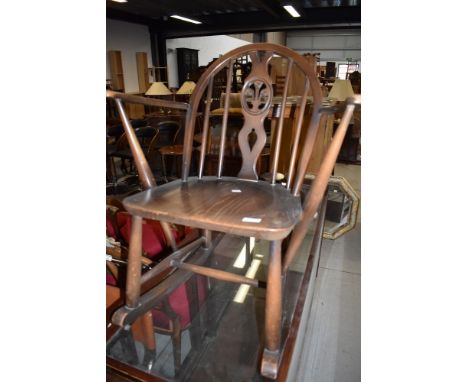 A childs low rocking arm chair in dark stain by Ercol having blue badge