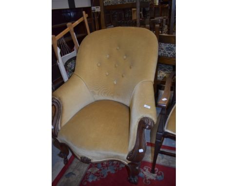 An early Victorian carved framed large salon chair having button back upholstery