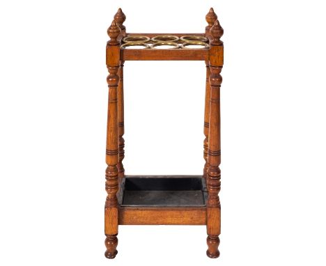 An oak and brass stick stand, circa 1900, with six circular divisions, urn finials and oblong metal drip trays at base, 41cm 