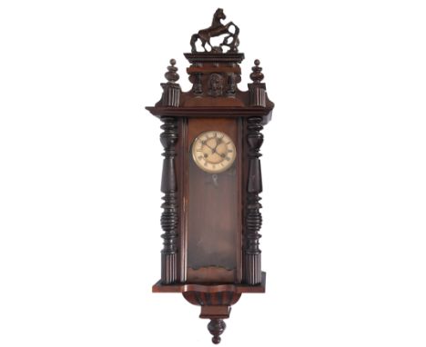 A late Victorian stained walnut wall clock, surmounted by a prancing horse with mask and urn finial, the circular enamel dial