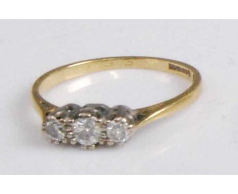 An 18ct gold and platinum diamond set three-stone ring, the round cut diamonds in a line setting, the larger centre stone wei