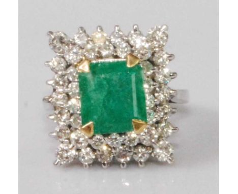 A contemporary white metal, emerald and diamond cluster ring, the four claw set square cut emerald weighing approx 2.2 carats