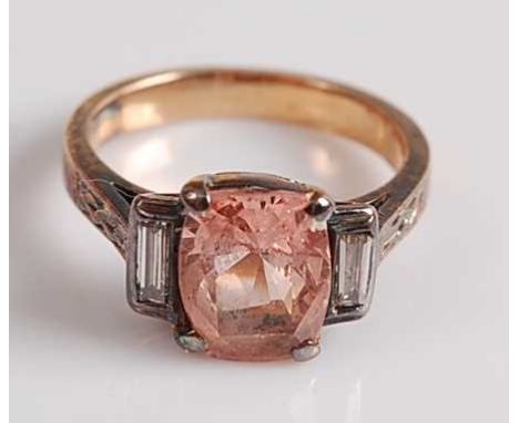 A yellow and white metal, pink sapphire and diamond ring, featuring an oblong pink sapphire with a baguette cut diamond to ei
