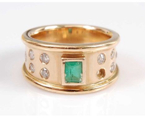 A yellow metal, emerald and diamond dress ring, comprising a centre rectangular cut emerald in a bezel setting, with five rou