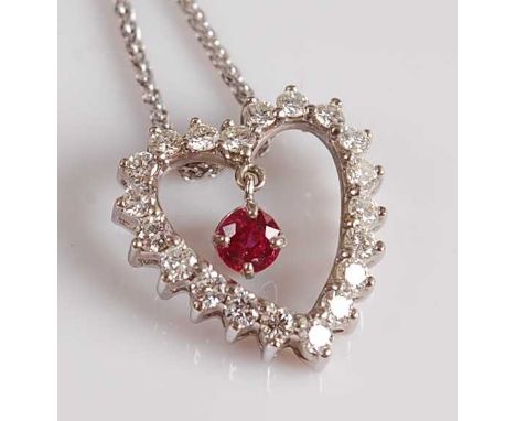 A white metal, ruby and diamond heart shaped pendant, featuring an articulated round faceted ruby within an open heart shaped