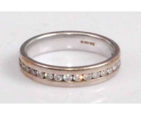 A contemporary 18ct white gold and diamond set half eternity ring, arranged as seventeen small channel set brilliants, sponso