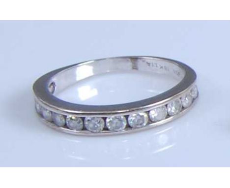 A white metal diamond half hoop eternity ring, comprising twelve round brilliant cut diamonds in channel settings, diamond di
