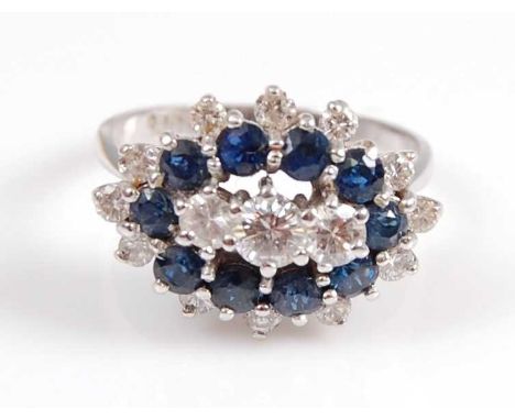 A white metal, sapphire and diamond marquise shaped reverse cluster ring, featuring a centre section of three graduated round