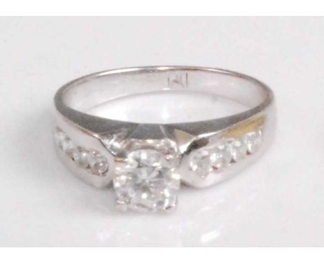 A contemporary white metal and cz set dress ring, arranged as a four claw set cubic zirconia flanked to either side with furt