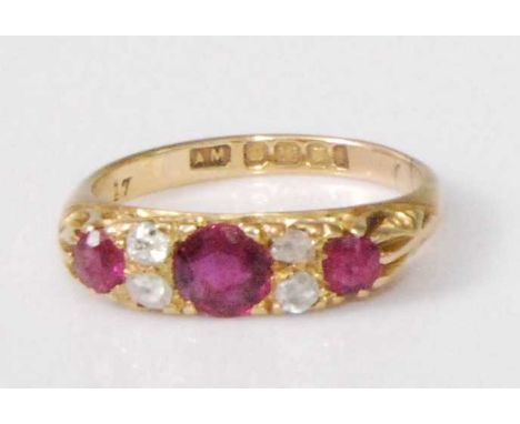 An Edwardian 18ct gold, ruby and diamond ring, arranged as three round cut rubies in a carved setting, the centre stone weigh