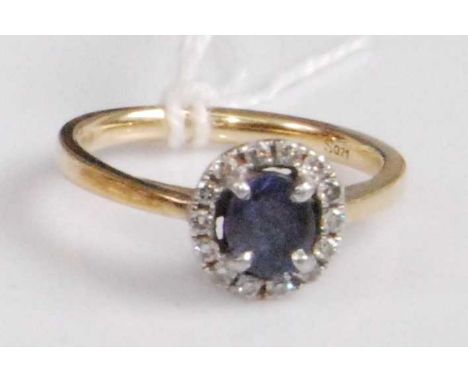 An 18ct gold, sapphire and diamond cluster ring, arranged as a four-claw set oval cut sapphire weighing approx 0.55 carats, i