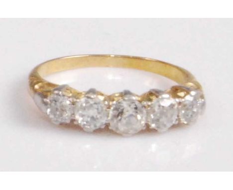 A yellow metal diamond five-stone ring, the slightly graduated old round cut diamonds in a carved line setting, the centre st