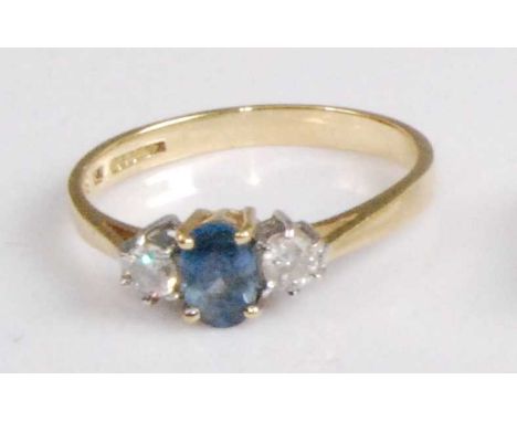 A modern 18ct gold, sapphire and diamond three-stone ring, the four claw set oval cut sapphire flanked to either side by a si