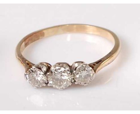 A yellow and white metal diamond three stone ring, the graduated round brilliant cut diamonds in claw settings, centre diamon