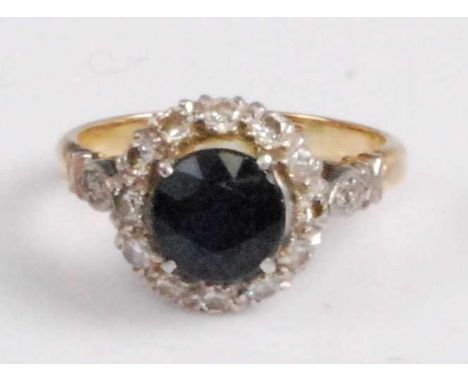 An 18ct gold and platinum, sapphire and diamond cluster ring, arranged as a centre round cut four claw set sapphire weighing 