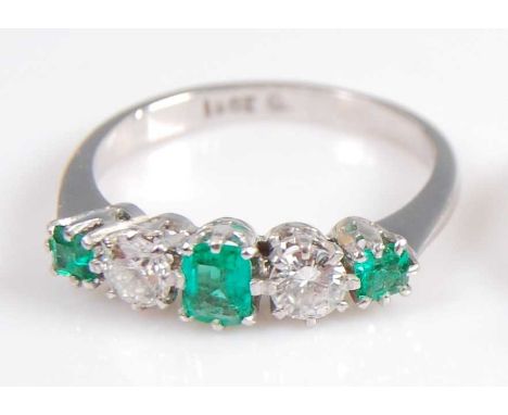 A white metal, emerald and diamond five stone half hoop eternity ring, featuring three graduated rectangular cut emeralds and