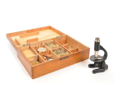 A mid 20th century cased miniature microscope, alongside a collection of slides. The microscope having a black cast metal bod