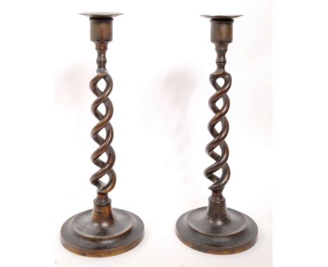 A pair of vintage brass candlestick holders. Circular stepped bases with open barley twist columns and flat saucer tops. Each